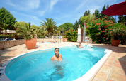 Donne si rilassano in piscina al Camping Les Pêcheurs, in Provenza-Alpi-Costa Azzurra, Francia, tra palme e fiori.