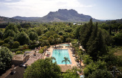Udsigt over swimmingpoolen på Camping Les Pêcheurs i Provence-Alpes-Côte d’Azur, Frankrig, omgivet af bjerge og træer.