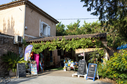 Negozio al Camping Les Pêcheurs in Provenza-Alpi-Costa Azzurra, Francia, circondato da verde e cartelli.