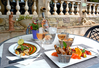 Feines Essen und Roséwein auf einem Terrassentisch im Camping Les Pêcheurs, Provence-Alpes-Côte d’Azur, Frankreich.