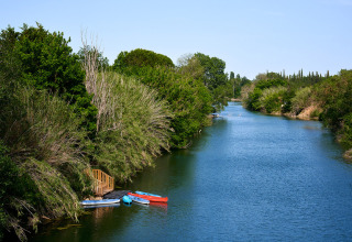 Fiume tranquillo circondato da alberi e barche colorate a Camping Les Pêcheurs in Provenza, Francia.