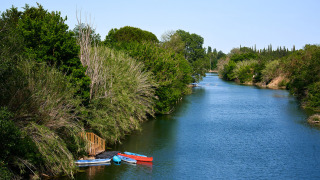 Río tranquilo con vegetación y barcas junto al borde en Camping Les Pêcheurs en Provenza, Francia.