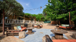 Zona de descanso al aire libre con sofás y mesas de madera, luces y árboles en Camping Les Pêcheurs.