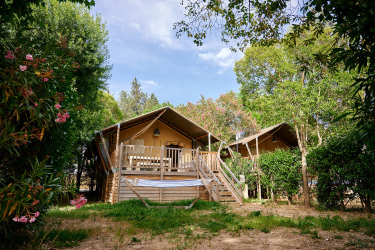 Houten hutten met veranda in een groene omgeving bij Camping Les Pêcheurs, Provence-Alpes-Côte d’Azur, Frankrijk.