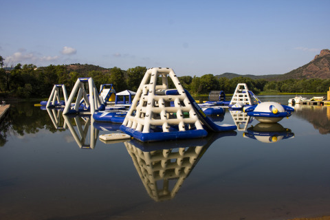 Parque acuático hinchable en Camping Les Pêcheurs, Provenza-Alpes-Costa Azul, Francia, rodeado de montañas.