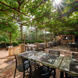 Buiten eetgedeelte bij Camping Les Pêcheurs in Provence-Alpes-Côte d’Azur met groene pergola en gedekte tafels.