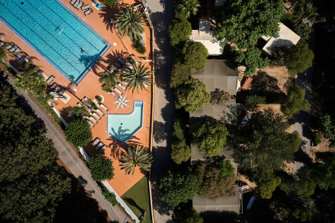 Aerial view of Camping Les Pêcheurs featuring two swimming pools, sun loungers, and shaded trees in France.