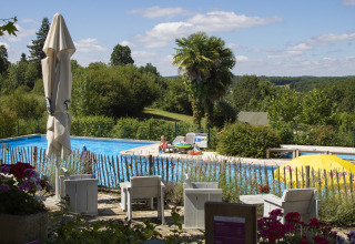 Udendørs swimmingpool på Camping Lestaubière i Nouvelle-Aquitaine, Frankrig, omgivet af grønne bakker.