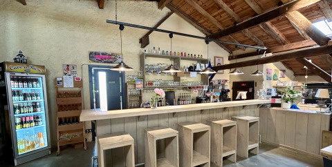 Bar interior en Camping Lestaubière, Nouvelle-Aquitania, Francia, con taburetes de madera y decoración rústica.
