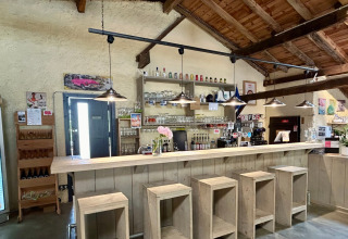 Bar interno al Camping Lestaubière in Nouvelle-Aquitaine, Francia, con sgabelli in legno e atmosfera rustica.