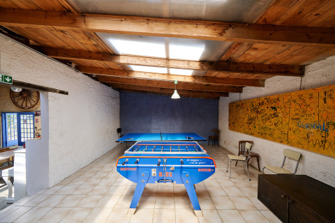 Sala de juegos en Camping Lestaubière, Nouvelle-Aquitaine, Francia, con futbolín y mesa de ping-pong.