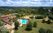 Luftfoto af Camping Lestaubière i Nouvelle-Aquitaine, Frankrig, med swimmingpool, sø og grønne marker.