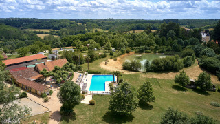 Vue aérienne du Camping Lestaubière, parc de vacances en Nouvelle-Aquitaine, France, avec piscine et étang.