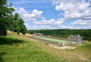 Outdoor-Sportplatz mit Holzzäunen auf einer Wiese und Blick ins Grüne bei Camping Lestaubière, Frankreich.