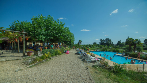 Camping Lestaubière en Nouvelle-Aquitaine, Francia, con piscina, tumbonas y huéspedes disfrutando al aire libre.