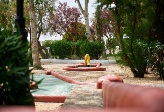 Et minigolfhul omgivet af grønne træer i Camping Nautic Almata feriepark i Catalonien, Spanien.
