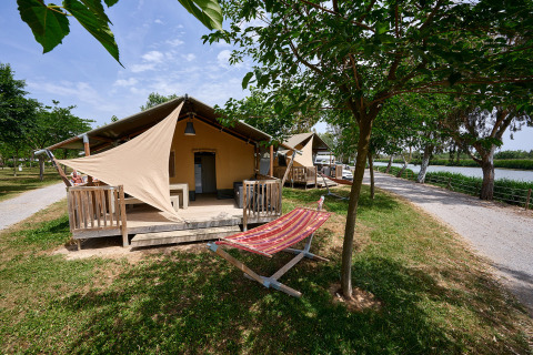 Cabañas glamping con porche y hamaca junto al río en Camping Nautic Almata en Cataluña, España.