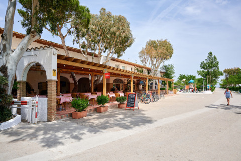 Ristorante all'aperto con tovaglie rosse e biciclette al Camping Nautic Almata, parco vacanze in Catalogna, Spagna.