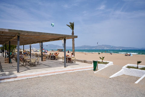 Vista de la playa en Camping Nautic Almata, Cataluña, España, con terraza al aire libre y personas relax.