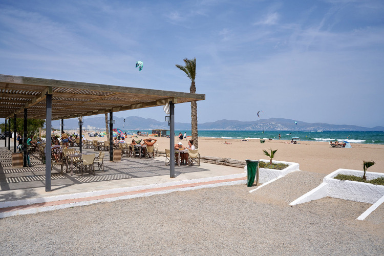 Vue plage au Camping Nautic Almata, Catalogne, Espagne avec terrasse extérieure et vacanciers détendus.