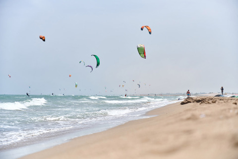 Kitesurfer cavalcano le onde presso Camping Nautic Almata, un villaggio turistico in Catalogna, Spagna.