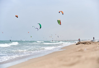 Kitesurfer cavalcano le onde presso Camping Nautic Almata, un villaggio turistico in Catalogna, Spagna.