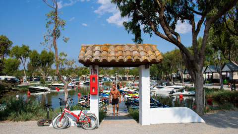 Vista en Camping Nautic Almata en Cataluña, España con barcos, bicicletas, árboles y bungalows.