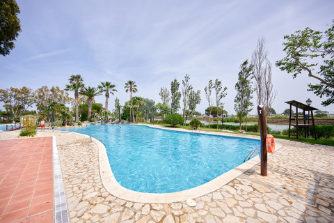 Swimmingpool im Camping Nautic Almata in Katalonien, Spanien, von Palmen und Natur umgeben.