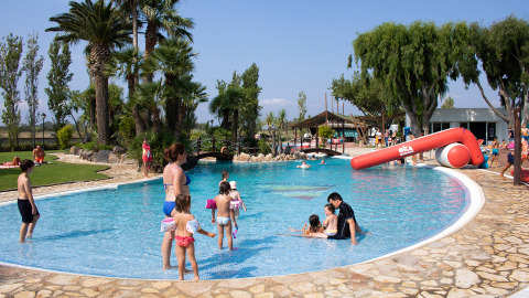 Familien mit Kindern genießen das Schwimmbad im Camping Nautic Almata in Katalonien, Spanien, bei Sonnenschein.