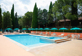 Buitenzwembad met ligbedden en parasols op Camping Pian Di Boccio in Umbrië, Italië.