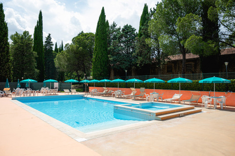 Piscina all'aperto con lettini e ombrelloni al Camping Pian Di Boccio in Umbria, Italia.