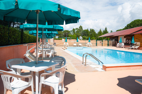 Piscina all'aperto con sedie bianche e ombrelloni blu al Camping Pian Di Boccio, Umbria, Italia.