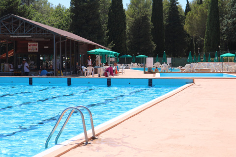 Piscina al aire libre con tumbonas, sombrillas y snack bar en el Camping Pian Di Boccio, Umbría, Italia.