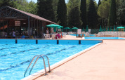 Outdoor swimming pool with sun loungers, umbrellas, and a snack bar at Camping Pian Di Boccio, Umbria, Italy.