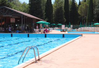 Outdoor swimming pool with sun loungers, umbrellas, and a snack bar at Camping Pian Di Boccio, Umbria, Italy.