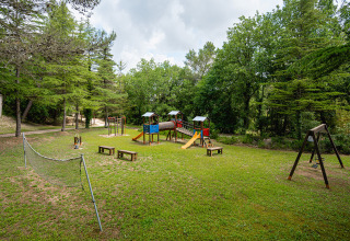 Legeplads omgivet af grønne træer på Camping Pian Di Boccio feriepark i Umbrien, Italien, med gynger og net.