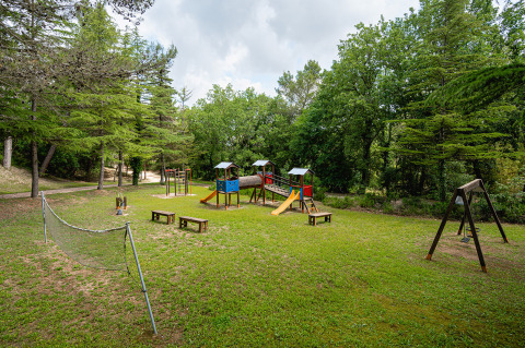 Parque infantil rodeado de árboles en Camping Pian Di Boccio, un parque vacacional en Umbría, Italia.