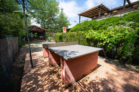 Table de ping-pong extérieure au Camping Pian Di Boccio en Ombrie, Italie, entourée de haies et d’arbres.