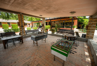Area comune coperta al Camping Pian Di Boccio in Umbria, Italia, con calcetti e posti a sedere.