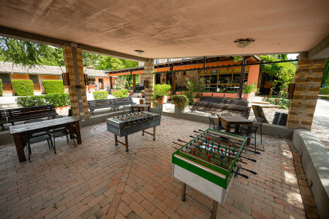 Area comune coperta al Camping Pian Di Boccio in Umbria, Italia, con calcetti e posti a sedere.