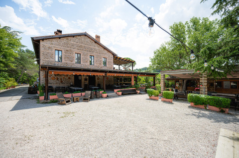 Außenansicht eines Steingebäudes und Innenhofs mit Sitzbereich im Camping Pian Di Boccio, Umbrien, Italien.