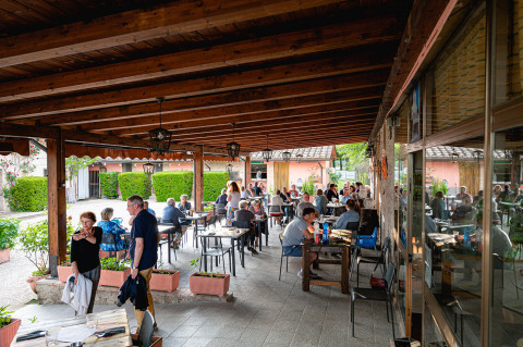 Terrasse couverte du Camping Pian Di Boccio en Ombrie, Italie, avec des convives partageant un repas.