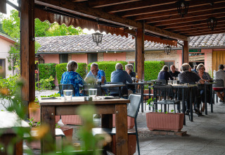 Udendørs restaurantområde på Camping Pian Di Boccio i Umbrien, Italien, med gæster der nyder maden.