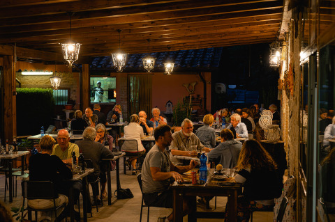 Personas cenando relajadamente en un restaurante al aire libre en Camping Pian Di Boccio, Umbría, Italia.