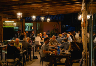 Gasten genieten van een diner op het gezellige terras van Camping Pian Di Boccio in Umbrië, Italië.
