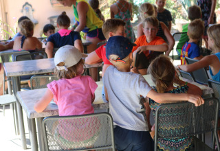 Kinder sitzen an Tischen und genießen Aktivitäten im Freien im Camping Pian Di Boccio, Umbrien, Italien.