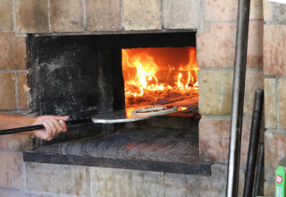 Een pizza wordt in een houtgestookte oven geschoven bij Camping Pian Di Boccio, een vakantiepark in Umbrië, Italië.