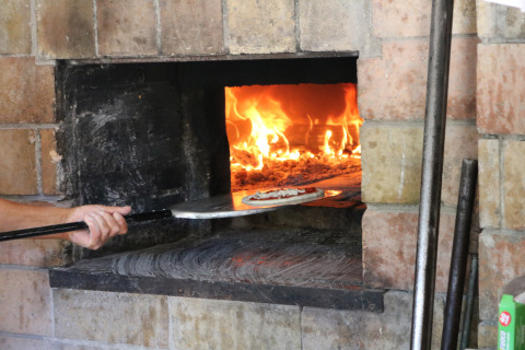 Una pizza viene cotta in un forno a legna al Camping Pian Di Boccio, un villaggio vacanze in Umbria, Italia.