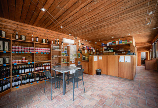 Indendørs reception og butik med trævægge og vinflasker på Camping Pian Di Boccio, Umbrien, Italien.