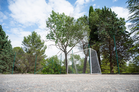 Porta da calcio in un campo sportivo circondato da alberi alti e recinzione a Camping Pian Di Boccio, Umbria, Italia.
